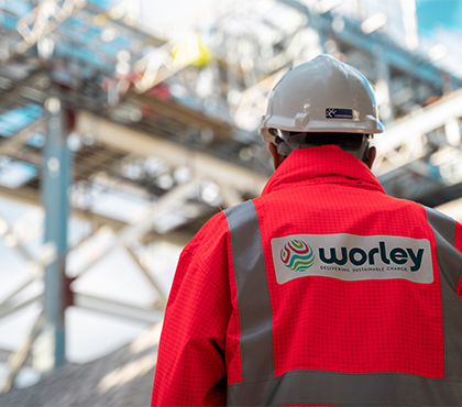 Back of a Worley person wearing PPE looking up to the steelwork.